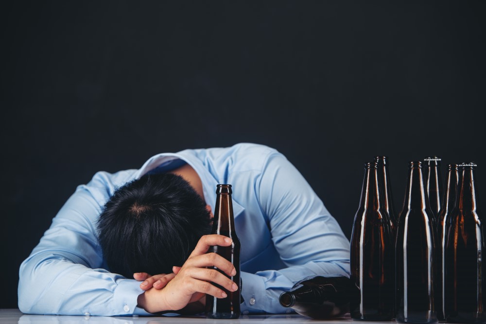 alcoholic asian man with lot beer bottles